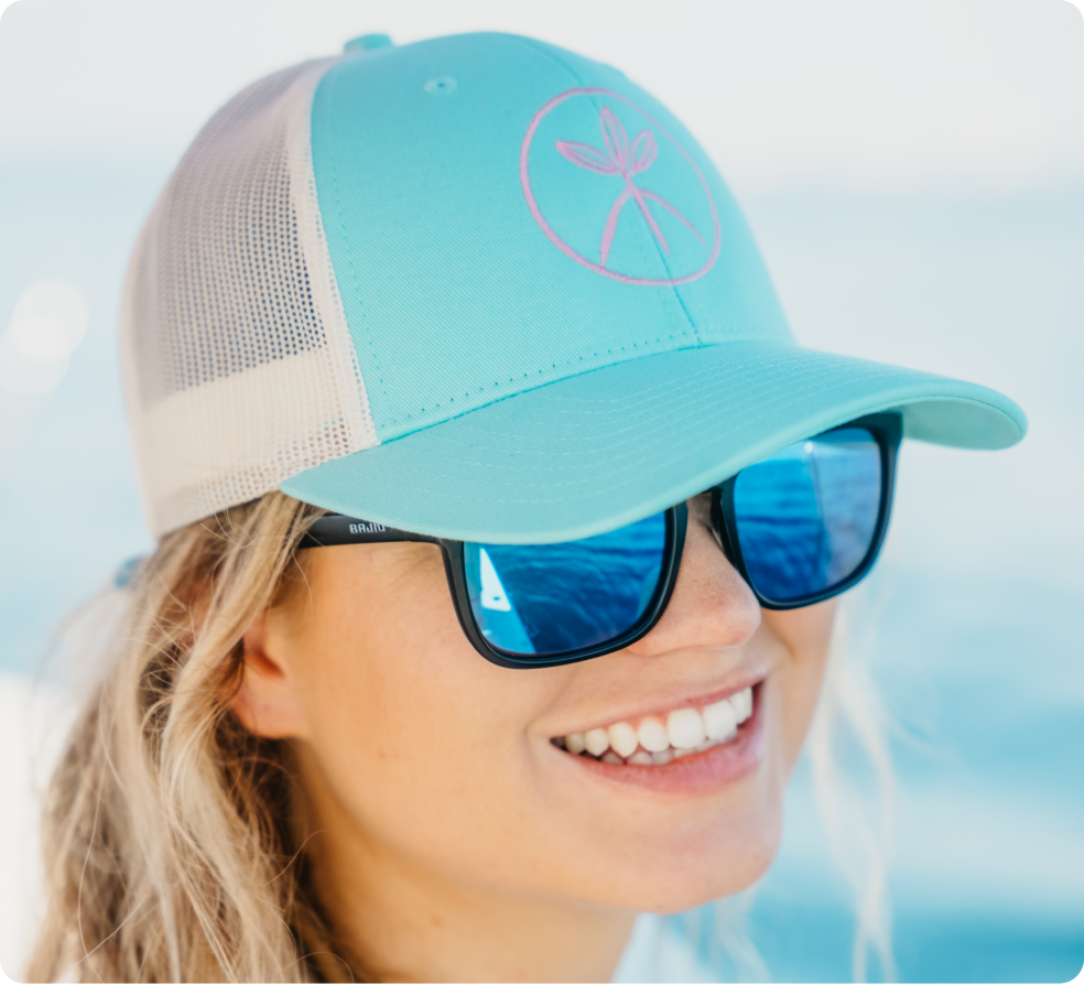Close-up of a woman wearing a turquoise MANG Tri-Leaf trucker hat