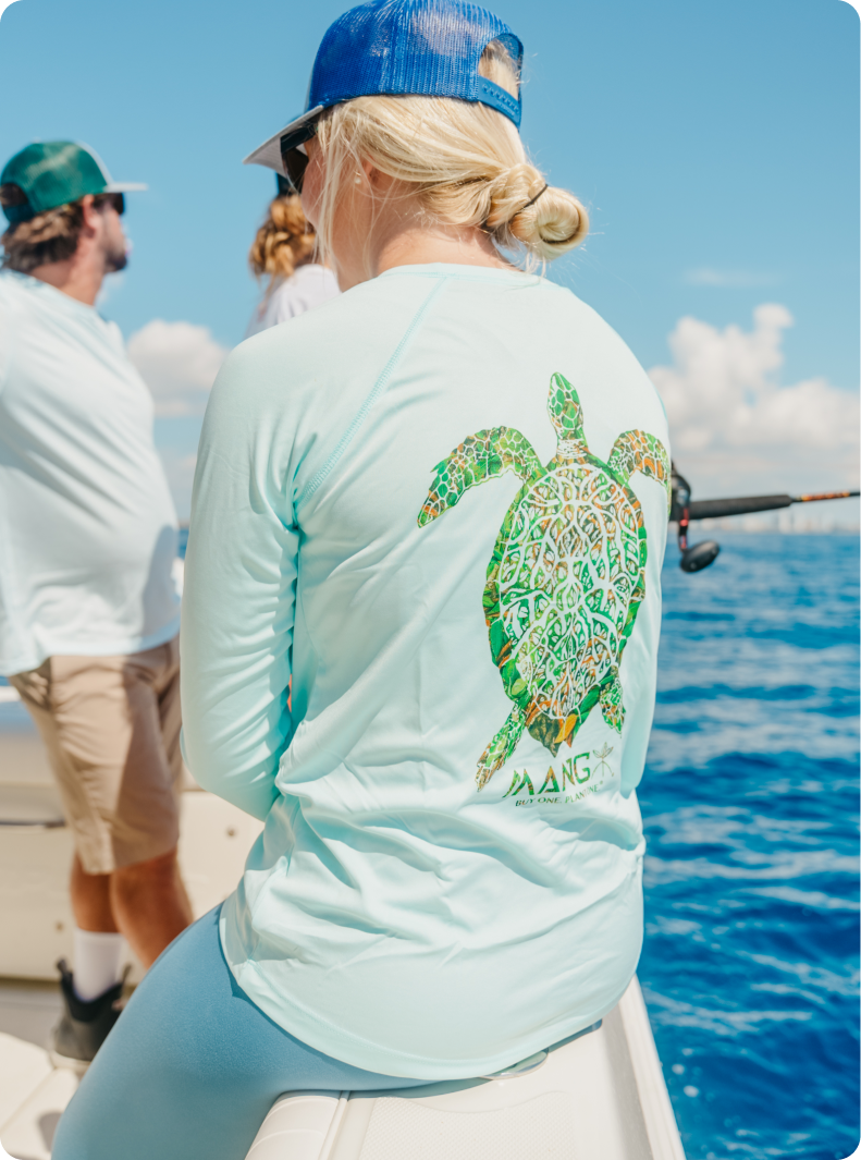 Close-up of a woman on a boat wearing a MANG Grassy Turtle performance long sleeve shirt