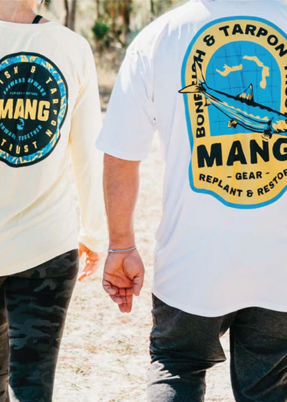 Young couple walking along a trail with MANG Bahamas Restoration Collection performance shirts on